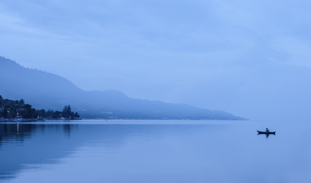 Lonely fisherman in foggy mountains, Lake Toba, Indonesia.