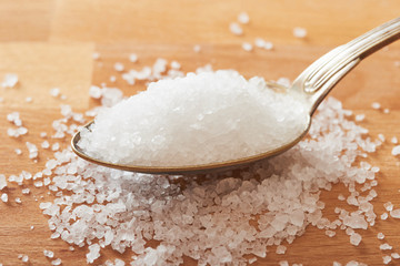Sea salt in a spoon on wooden table