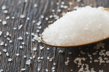 Sea salt in a spoon on wooden table