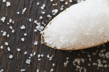 Sea salt in a spoon on wooden table