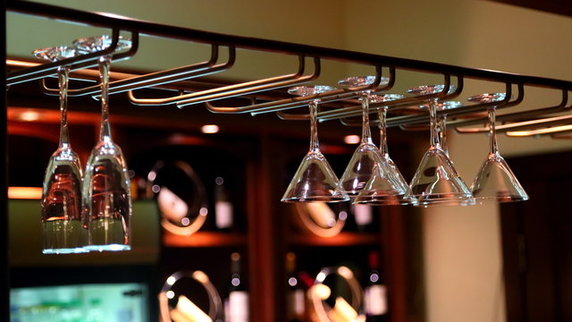 Empty clean wine glasses are hanging above the bar