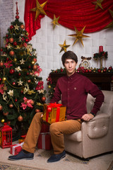 Happy young man with a gift in hands near Christmas trees winter New year