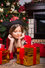 Beautiful girl with gifts in a red dress near Christmas tree winter New year