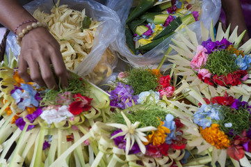 Colorful Balinese Hindu Offerings. Hindu offerings, called canang, are being made and sold at the Ubud village traditional public market. Flowers and palm leaves woven together make a beautiful piece.