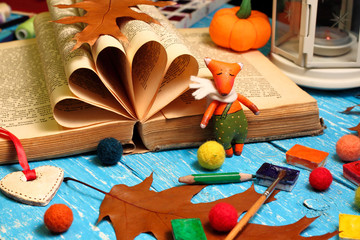 Toy fairytale little fox with a book, autumn oak leaves, a spool of thread and pencils
