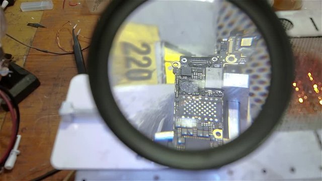 Engineer preparing motherboard of smartphone iphone to repair. White man in old workshop.