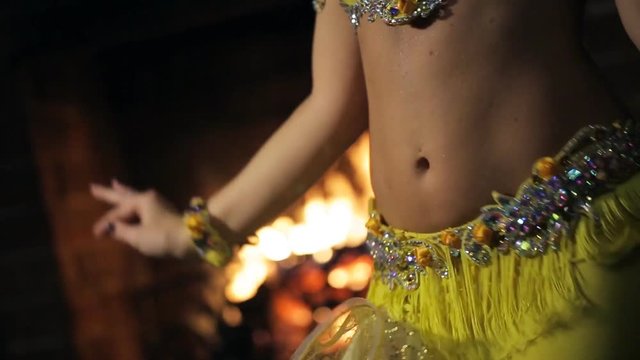 Woman in a yellow dress on a background of fire dancing belly dance.