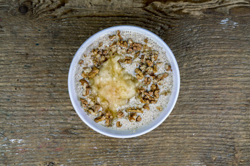 Overhead view of bowl of cereal with nuts on old wooden table