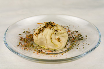 Closeup of ball of dough covered in fresh herbs on glass plate