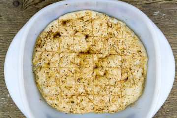 Overhead view of raw garlic bread in baking dish with criss-cross pattern