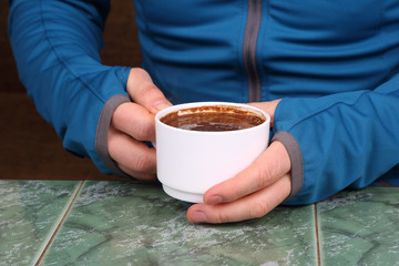 hands in next to a hot cup of coffee