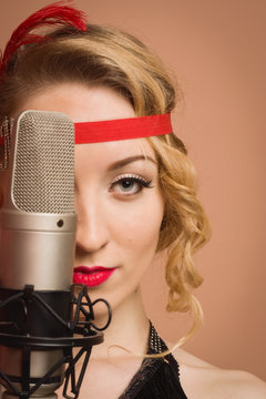 Pretty actress in black retro dress singing with microphone