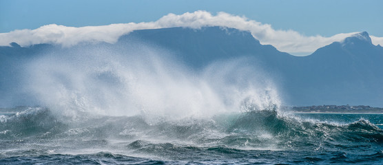 Seascape.  Clouds sky, waves with splashes, mountains silhouettes. False bay. South Africa.