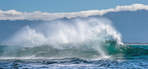 Seascape.  Clouds sky, waves with splashes, mountains silhouettes. False bay. South Africa.