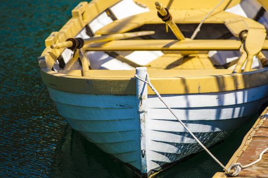 yellow and white empty wooden row boat tied to dock