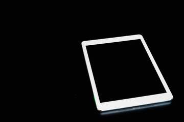 White digital tablet on blackwooden table