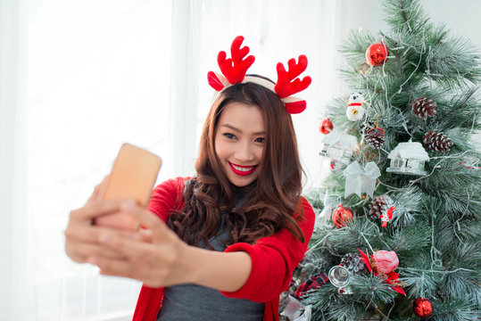 Woman take selfie on phone with Christmas hat hold christmas gif