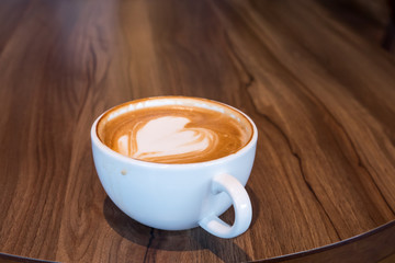 Delicious hot coffee in white cup on wooden table