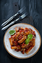 Italian ziti over black wooden background, high angle view