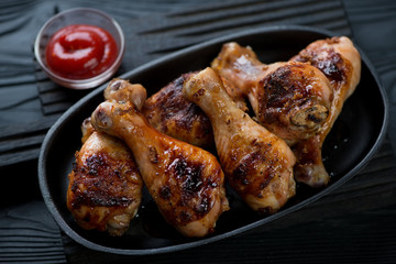 Close-up of a frying pan with grilled chicken legs and sauce