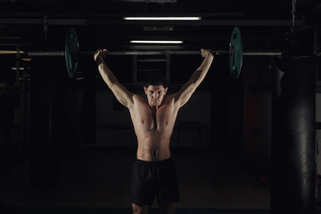 Fototapeta na wymiar Muscular man at a crossfit gym lifting a barbell.