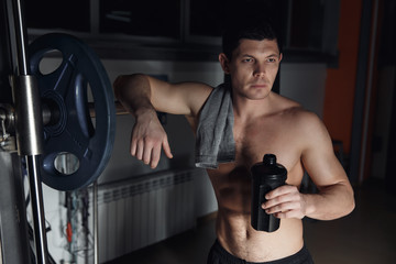 Fototapeta na wymiar guy bodybuilder tired in gym hold shaker with sportive nutrition - protein of shaker.