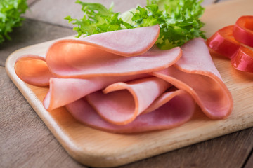 Sliced ham on wooden plate