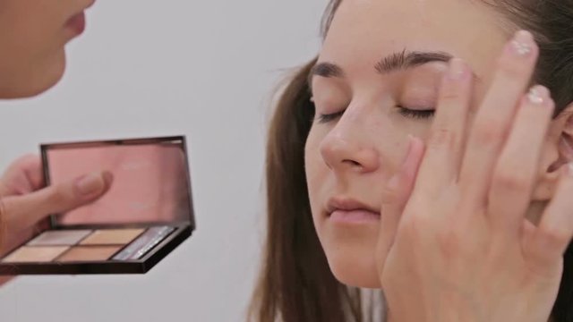 Close up shot. Professional make-up artist applying cream base eyeshadow primer to model eye. Beauty, makeup and fashion concept