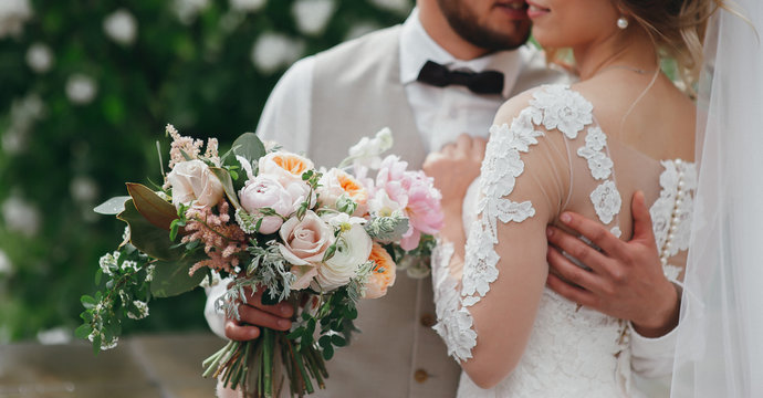 stylish bride and groom are holding bridal bouquet