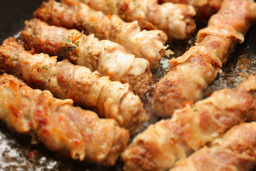 Roasted meat in a pan with bacon chevapchichi. Photo with bokeh effect
