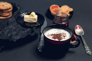 Cup of coffee, cappuccino with chocolate cookies and biscuits on black table background. Afternoon break time. Breakfast.