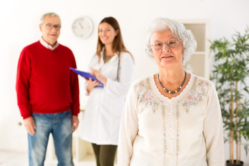 Senior woman smiling with her husband and doctor in background