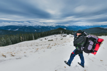 Fototapeta na wymiar Tourist photographer takes pictures of winter mountains