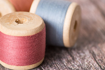 
Sewing.   Old wooden coils with sewing thread on a wooden background.