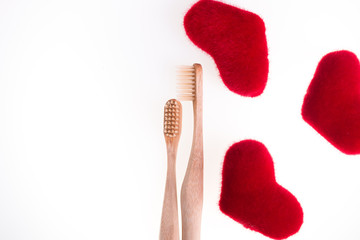 Two beige dental brushes with red hearts on white background. Isolated.  Love. Valentine day. Top view. Copy space.
