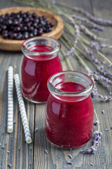Black currant, greek yogurt, honey and lavender smoothie in glass jar with berries and flowers on background, vertical