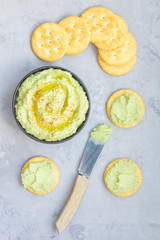 Healthy avocado hummus sprinkled with olive oil, paprika and sesame, served with crackers, vertical, top view