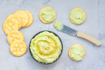 Healthy avocado hummus sprinkled with olive oil, paprika and sesame, served with crackers, horizontal, top view