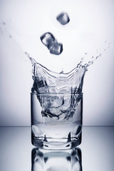 glass of water and ice on a white background with splashes
