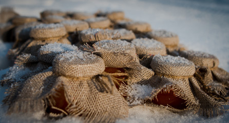 Jars with mandarin jam on a snow covered with burlap cover