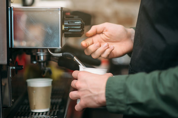 Man hands pours drink from a coffee machine.