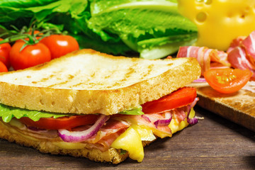 grilled sandwich or panini with bacon, cheese, lettuce, onion, tomatoes