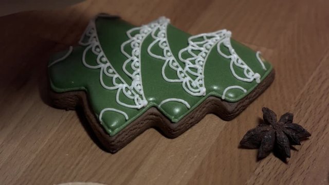 Female hand decorate Gingerbread green tree cookie with food icing on the table, close up.