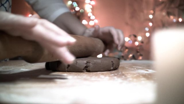 Female hand rolled fresh dough on the table with the help of a rolling pin. Dolly shot. Fresh flour is scattered around. fresh ginger dough for the Gingerbread cookie. close up, dolly shot. Bokeh back