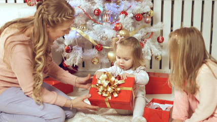 Family consists of the females sitting around the Christmas tree with gifts