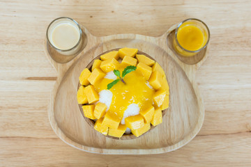 Bingsu ( Korea food) mango served with sweetened condensed milk on table