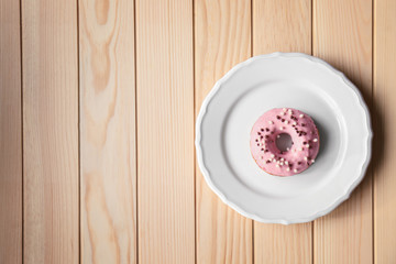 Fototapeta na wymiar Plate with delicious donut on wooden background