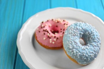 Plate with delicious donuts on blue wooden background