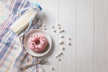 Plate with delicious donut and bottle of milk on table