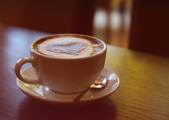 Cup with hot tasty coffee on wooden table in cafe, close up view